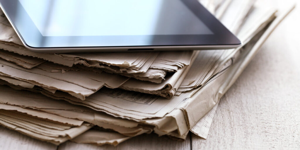 iPad appoggiato su una pila di giornali. Documenti appoggiati su un tavolo.